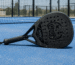 Raquette de padel NRV Phantom noire sur un court bleu